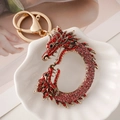 Golden dragon keychain with red and pink rhinestones on a white shell plate - Red