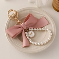 Pink ribbon bow keychain with faux pearl strand and gold-tone rhinestone charm detail - Pink