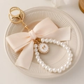 Elegant beige bow keychain with pearl chain and golden enamel pendant for handbags - Off-white