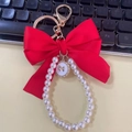 Red satin bow keychain with white pearl strand and golden metal ring for bags - Red
