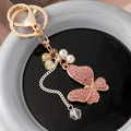 Portachiavi con farfalla di strass rosa, finitura dorata, perle e ciondoli in cristallo - Rosa