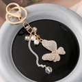 Elegante portachiavi a farfalla dorato con strass, perle e nappina in cristallo lucido - Bianco