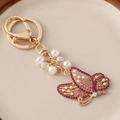 Golden butterfly keychain with purple rhinestones, faux pearls, and lobster clasp for bags - Pink