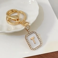 Elegante portachiavi dorato con lettera T incastonata di strass su smalto bianco - Lettera T