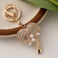 Golden palm tree keychain with crystal rhinestones and white pearls on a ceramic plate - Gold