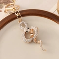 Porte-clés serpent doré avec cristaux brillants et fermoir mousqueton sur un plat en céramique - Blanc