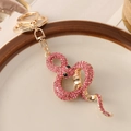 Porte-clés serpent avec strass roses et finition dorée sur une assiette décorative - Rose