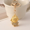 Gold Monkey King keychain with sparkling rhinestones leaning on a white ceramic cup - Sun Wukong (Monkey King) / Matte Gold