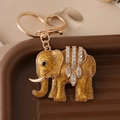 Luxe gouden olifant sleutelhanger met glitters en strass steentjes op bruine decoratie - Goud