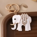 Witte emaille olifant sleutelhanger met goudlaag en glanzende kristallen op een dienblad - Wit