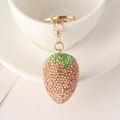 Detail eines kreativen Strass-Erdbeere-Schlüsselanhängers an einer Tasse - Champagner