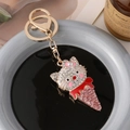 Cartoon cat ice cream keychain with white rhinestones and pink bow on gold metal ring - Red