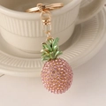 Portachiavi a forma di ananas rosa con strass appeso al bordo di una tazza bianca - Rosa