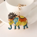 Golden elephant keychain with yellow rhinestones and enamel patterns on a white cup - Black