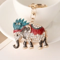 Golden elephant keychain with white rhinestones and red ethnic patterns on a white cup - Blue
