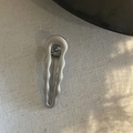 Nahaufnahme einer silbernen Wellen-Haarklammer mit Metallic-Finish auf Leinenstoff - Glänzendes Wellenmuster Design