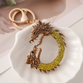 Llavero de dragón dorado con diamantes ámbar sobre un plato blanco decorativo - Amarillo