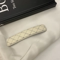 Detailed macro view of cream-colored faux leather hair clip with diamond lattice stitching - Off White
