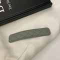 Macro shot of bean green leather hair clip with classic quilted diamond stitching texture - Blue Gray