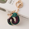 Golden dragon keychain with green and purple enamel finish on a white book - Purple