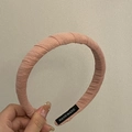 Detail of pink fabric headband with pleated texture and handmade label showing craftsmanship - Pink