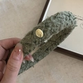 Nahaufnahme eines dunkelgrünen Tweed-Haarreifens mit polierter goldener Metallschnalle - Grün