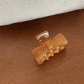 Detailopname van een kleine amberkleurige acetaat strik haarklem op een rustieke achtergrond - Strik Haarklem / Tortoise