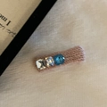 Detail van een gebreide haarklem met drie fonkelende kristallen op een getextureerde mat - Roze