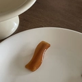 Dettaglio del fermaglio ondulato in resina ambrata con scritta fatta a mano su un piatto - Tartarugato Onda (6#)