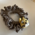 Detailed close-up of handmade brown knit hair tie with yellow wool felt animal decoration - Yellow Tiger Grey