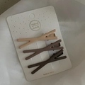 Dettaglio di tre fermagli per capelli marroni opachi su un cartoncino su sfondo di tessuto - 1# Assortimento di Incrocio al Tè al Latte