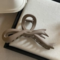 Pinza per capelli marrone scuro opaco a forma di fiocco con texture satinata su fondo di stoffa - caffè