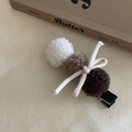 Detailed view of hair clip with cream fleece balls and a woven bow on beige fabric - Milk Tea Plush Ball Duckbill Clip
