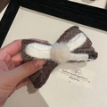 Dettaglio del fermaglio a fiocco in maglia marrone con pompon crema e bordi in lana - Becco d'Anatra (5#) / Fiocco Bianco Medio Cachi Pompon