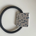 Detailaufnahme von einem Haargummi mit quadratischem Marmormuster und Gravur-Schmuck - Weiß mit blauen Punkten Quadrat