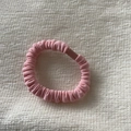 Detail of pink pleated fabric hair scrunchie with matte clip on waffle texture background - Pink Hair Tie