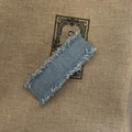 Vintage Denim-Haarspange in gewaschenem Blau mit Fransen auf rustikalem Textilhintergrund - Hellblau Ausgefranster Stil