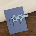 Close-up of light blue hollow star hair clips on purple handmade display card - Blue