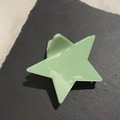 Macro detail of a star-shaped macaron green hair claw clip on a dark textured stone - Green Pentagram