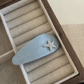 Close-up of a light blue denim star hair clip on a beige velvet jewelry display tray - Light Denim Water Drop Star Style
