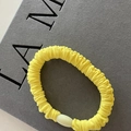 Detalle del coletero de tela arrugada amarillo brillante con elegante perla crema - Amarillo
