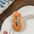 Vista de detalle de una horquilla ondulada naranja sobre un plato de cerámica decorativo - Naranja
