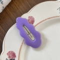 Detalle de una pinza para el pelo morada en forma de onda sobre plato decorado - Morado