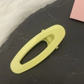Minimalist hollow oval hair clip in pastel yellow finish on a grey slate surface - Yellow