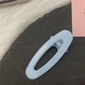 Detail of light blue oval hair clip with smooth resin finish on dark stone background - Blue