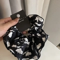 Dettaglio macro di un elastico per capelli con stampa a inchiostro e cartellino - Base Nera Foglia Bianca Scrunchie