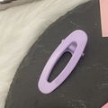 Detailed view of a light purple hollow oval hair clip on a minimalist textured background - Purple