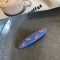 Primer plano de una pinza ovalada azul con lazos naranjas sobre fondo de lona - Azul