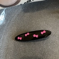 Primer plano de una pinza negra brillante con cuatro diseños de lazos rosas - Negro