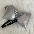 3D metallic silver bow hair clip with white woven label on a soft white plush background - Silver Bow BB Clip
